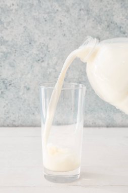 Sütü bir galon şişeden masaya dökerek.