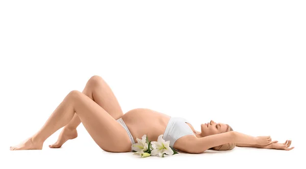 白い背景に横たわっているユリの花を持つ美しい妊婦 — ストック写真