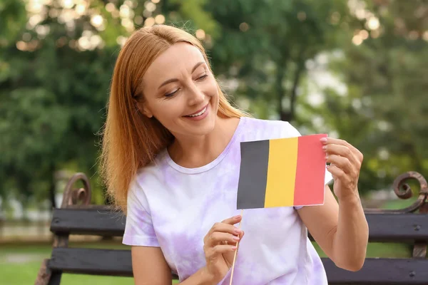 拿着比利时国旗的成熟女人坐在公园的长椅上 — 图库照片
