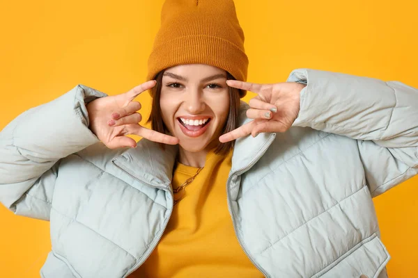 Renkli arka planda şık ve sıcak kıyafetler giyen havalı genç bir kadın.