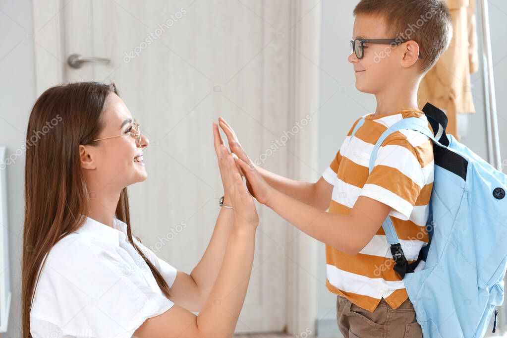 Woman and her little son giving each other high-five before school