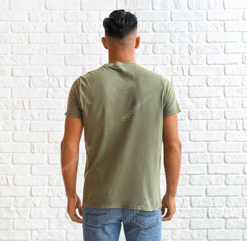 Handsome young man in stylish t-shirt on white brick background, back view