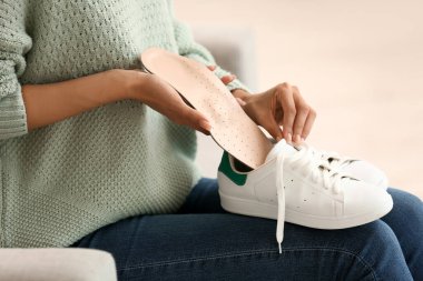 Kadın spor ayakkabısına ortopedik taban yerleştiriyor, yakın plan.