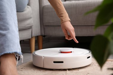 Modern robot elektrik süpürgesi odada bir kadının yanında.