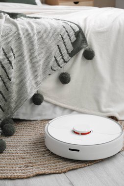 Modern robot süpürge odada yatağın yanında.