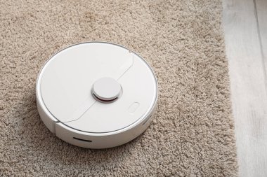Modern robot süpürgesi yumuşak halıda.