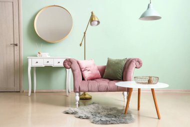 Pembe koltuklu, altın lambalı ve yeşil duvarlı şık bir oda.