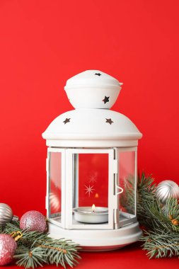 Güzel Noel feneri yanan mum, köknar dalları ve kırmızı arka planda toplar