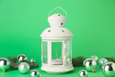 Yeşil arka planda yanan mum, toplar ve köknar dallarıyla güzel bir Noel feneri.