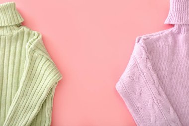 Pembe arka planda örülmüş yuvarlak yakalı kazaklar.
