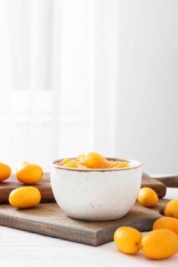 Bir kase lezzetli kumkat reçeli ve mutfak masasında taze meyve.