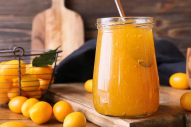 Bir kavanoz lezzetli kumkat reçeli ve ahşap zemin üzerinde taze meyveler.