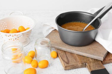 Taze kumkatlı çömlek reçeli ve beyaz arka planda taze meyve.