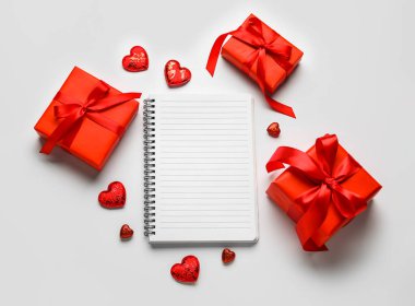 Arkaplanda hediyeler olan boş bir defter. Sevgililer Günü kutlaması