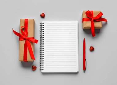 Gri arkaplanda hediyeler olan boş bir defter. Sevgililer Günü kutlaması