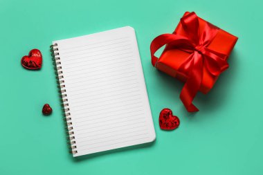 Renkli arka planda hediyesi olan boş bir defter. Sevgililer Günü kutlaması