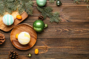 Banyo bombası, kumkat meyveleri, Noel topları ve ahşap arka planda köknar dalları olan kompozisyon