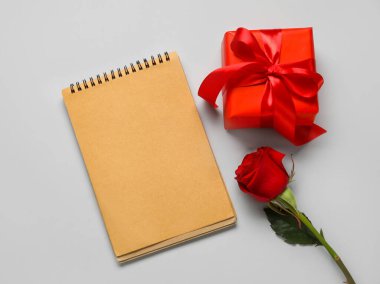Hediyeli boş defter ve açık arkaplanda gül çiçeği