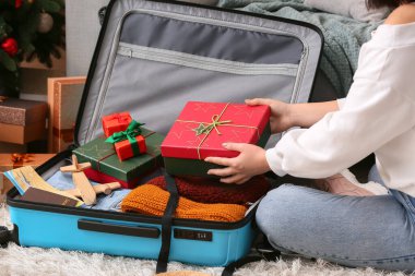 Evde Noel hediyelerini çantaya koyan bir kadın.