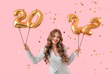 Renkli arka planda 2022 şeklinde balonları olan güzel genç bir kadın. Yeni yıl kutlaması