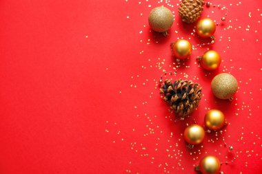 Kırmızı arka planda şık Noel baloları ve köknar konileri