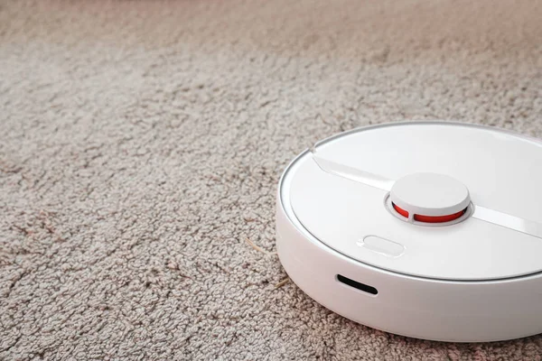 Modern robot süpürgesi yumuşak halıda.