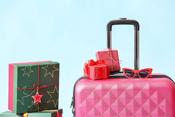 Pinkfarbener Koffer Mit Sonnenbrille Und Weihnachtsgeschenkschachteln Auf Blauem Hintergrund — Stockfoto