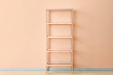 Pembe duvarın yanındaki boş ahşap raf ünitesi.