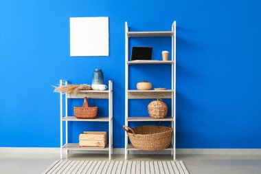 Dekorlu raf ünitesi, dizüstü bilgisayar ve mavi duvarın yanında bir fincan kahve.