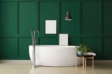 Yeşil duvarın yanındaki boş çerçeveli modern küvet.