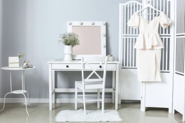 Masası, katlanmış ekranı ve vazosu olan hafif soyunma odasının içi.