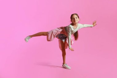 Pembe arka planda dans eden sevimli küçük kız