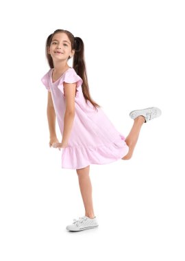 Beyaz arka planda dans eden pembe elbiseli sevimli küçük kız.