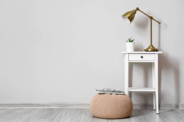 Lambalı masa ve ışık duvarının yanında puf.