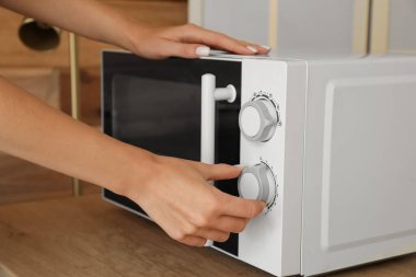 Mutfakta mikrodalga fırını açan kadın, yakın plan.