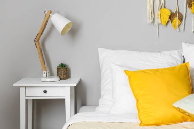 Modern lamba ve saksı komodinin yanında, ışık duvarının yanında.