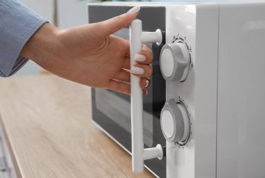 Mutfakta mikrodalga fırın kullanan kadın, yakın plan.