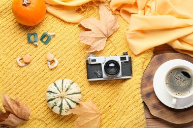 Şık bir süveter, kadın aksesuarları ve tahta arka planda bir fincan kahve.