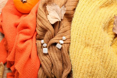 Ahşap arka planda zarif kadın kazakları ve küpeleri.