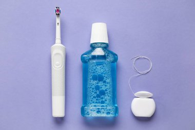 Mor arkaplanda diş ipi, durulama ve elektrikli diş fırçası.