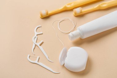 Diş ipi, kürdan, fırça ve yapıştırıcı bej arka planda