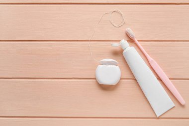 Diş fırçalı diş ipi ve pembe ahşap arka planda yapıştırıcı.