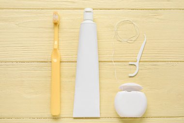 Sarı ahşap zemin üzerinde kürdan, yapıştırma ve fırça ile diş ipi