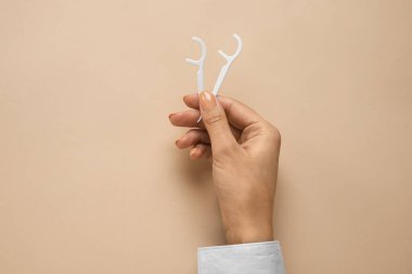 Bej arkaplanda diş ipi olan bir kadın.