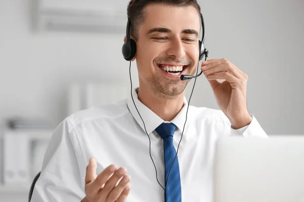 Answering male consultant of call center with headset in office