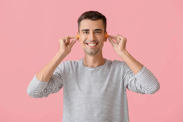 Sonriente Joven Poniendo Tapones Para Los Oídos Sobre Fondo Rosa —  Fotos de Stock