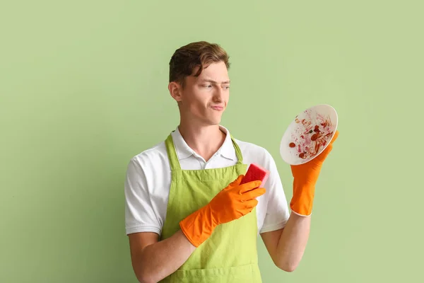 Displeased Young Man Cleaning Sponge Dirty Dish Green Background — Stock Photo, Image
