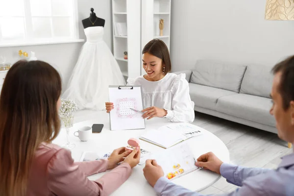 Female wedding planner discussing ceremony with clients in office