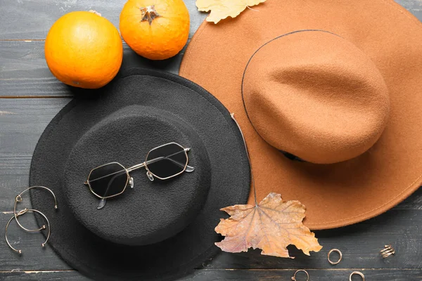 Koyu ahşap arka planda şık şapkalar, balkabağı ve kadın aksesuarları.