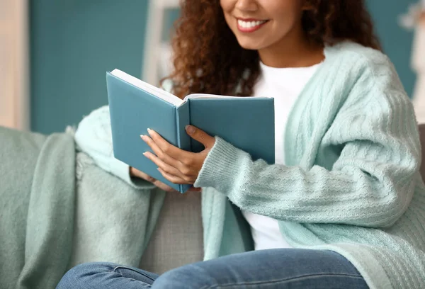 Young African American Woman Blue Cardigan Reading Book Sofa Home — Stock Photo, Image